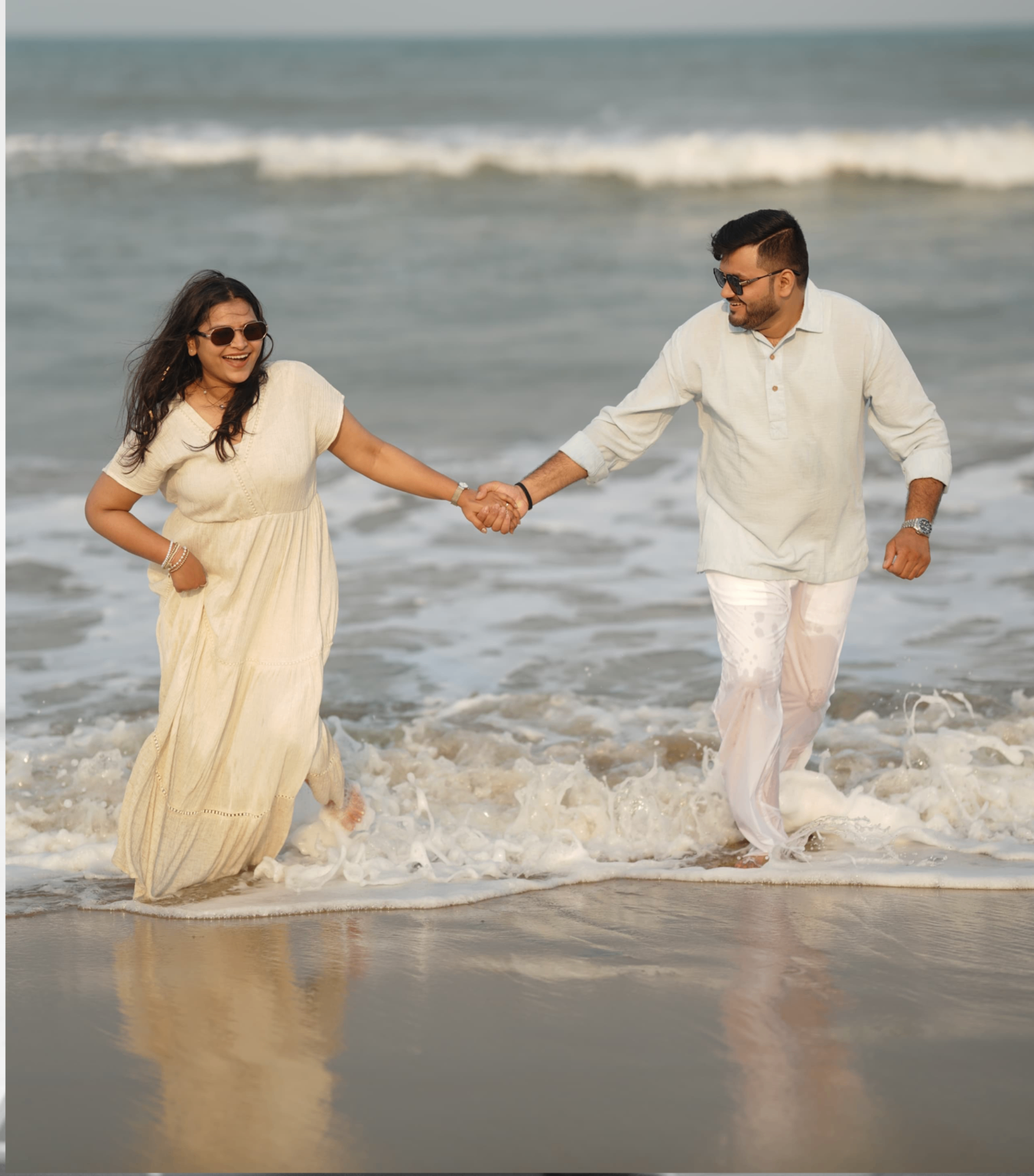 Saloni and Dharshan running through the waves on the beach